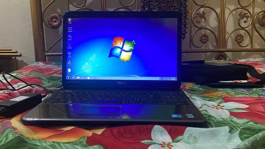 Dell Inspiron N5010 laptop with a silver chassis and a large keyboard.