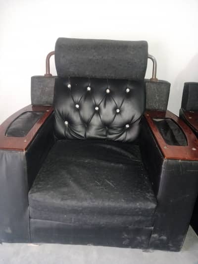 This black leather armchair features distinctive tufted back cushioni