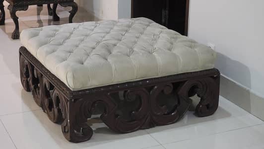 Tufted ottoman with carved wooded base