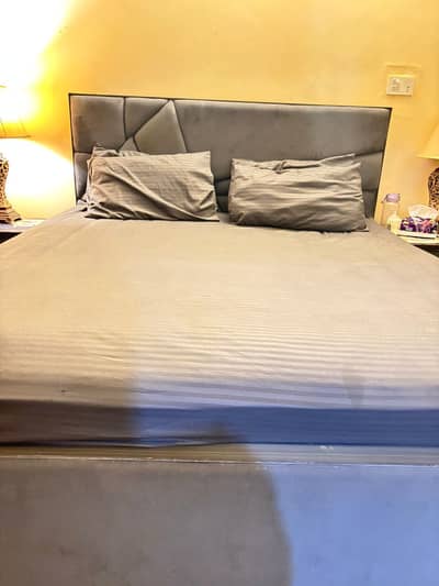 A cushioned Bed set with king size bed 02 sides a dresser n a tv wall