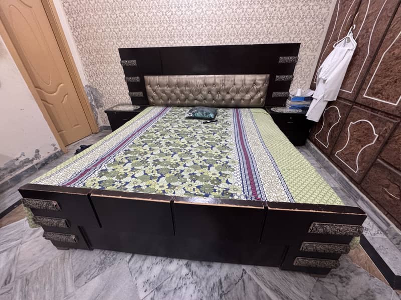 A king size bed and two side tables  and dressing table 0