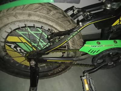 neon green kids cycle with traing wheels also has chain gard