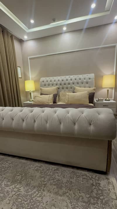 Bed set with side tables and lamps and corner chair with foot rest