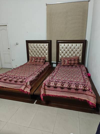 A pair of single beds with spring mattresses, both in good condition