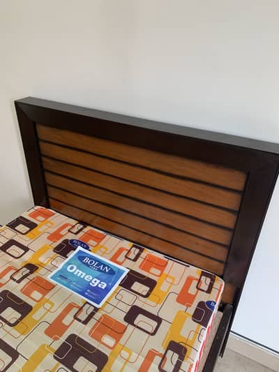 Wooden single bed with mattress.