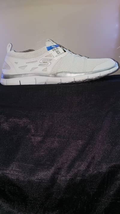silver athletic skechers with a mesh upper and stretch laces
