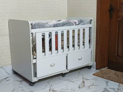 white wooden baby cot with built-in storage drawers