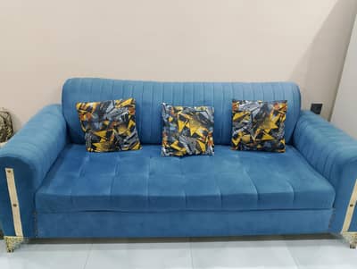 6 seater Blue colored sofa along table