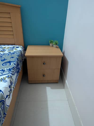 Single bed with side table and mattress.