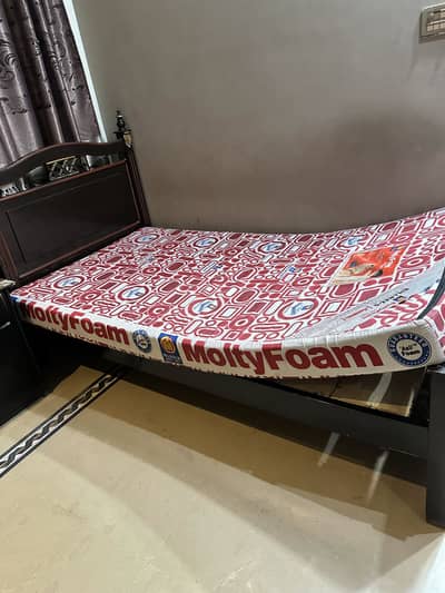 Single wooden bed with molty foam mattress and a side table