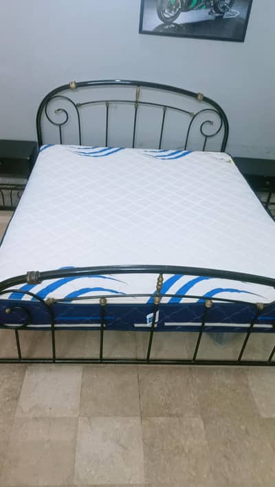 rod iron bed with 2 side tables and a mattress king sized