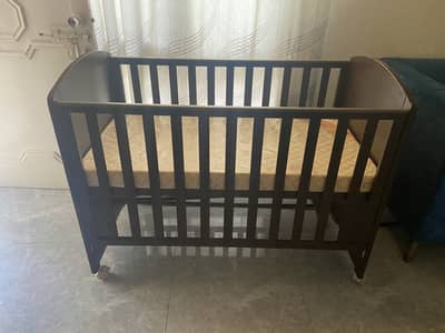 Tinnies brown wooden baby cot with mattress .
