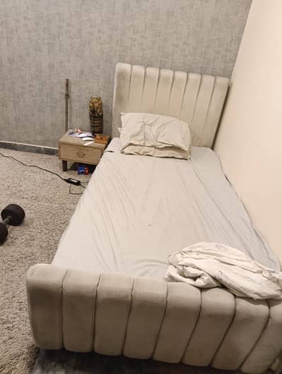 single quilted bed with mattress and side table