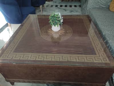 large wooden square center table with glass top and versace border.