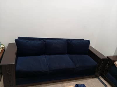 Three seater sofas in blue velvet with two side tables.